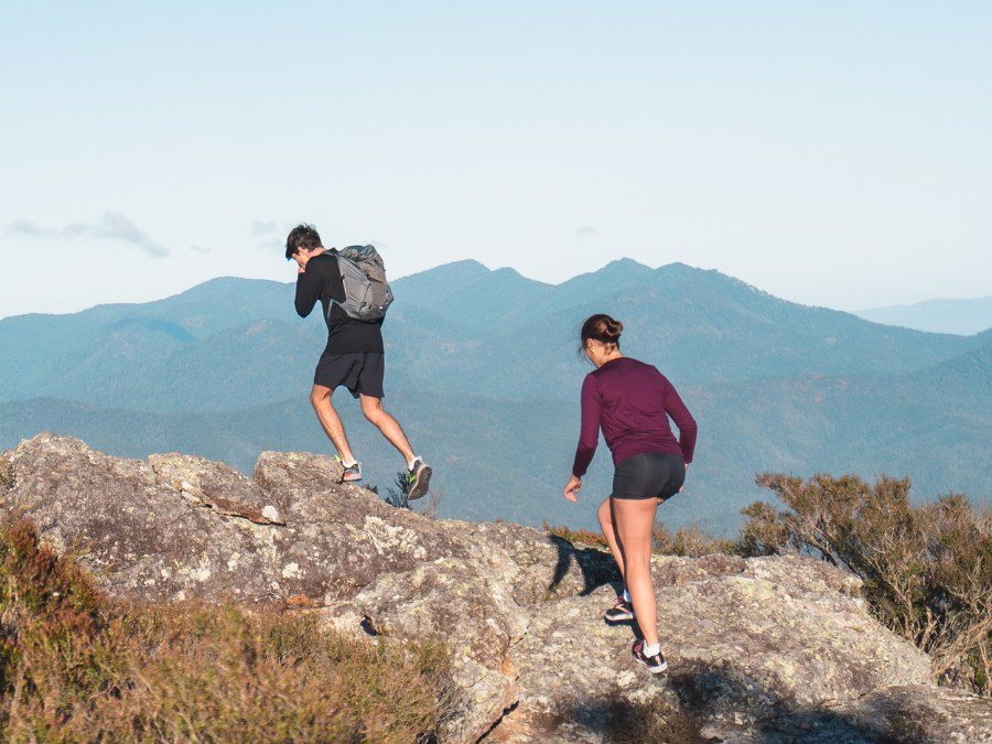 Two hikers stepping across summit rocks